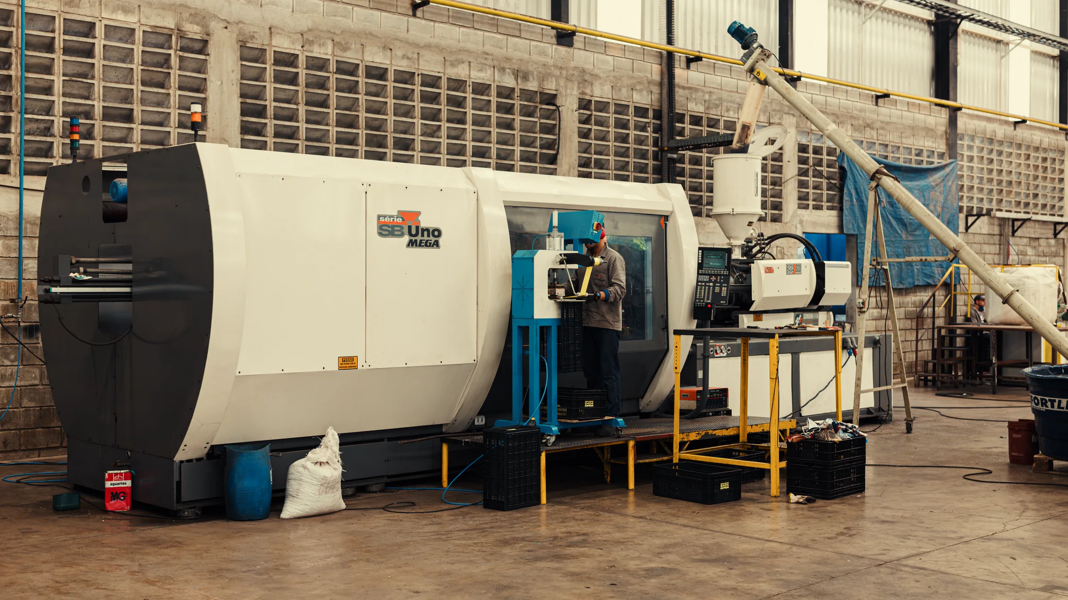 Máquina industrial de injeção em operação na fábrica da Koprum
